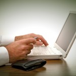 man sitting at desk placing order with credit card on laptop with wallet