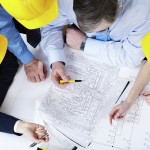 Above view of four architects sitting at the table and discussing design project