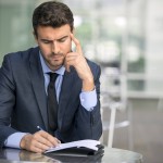 Focused businessman thinking and writing outside office